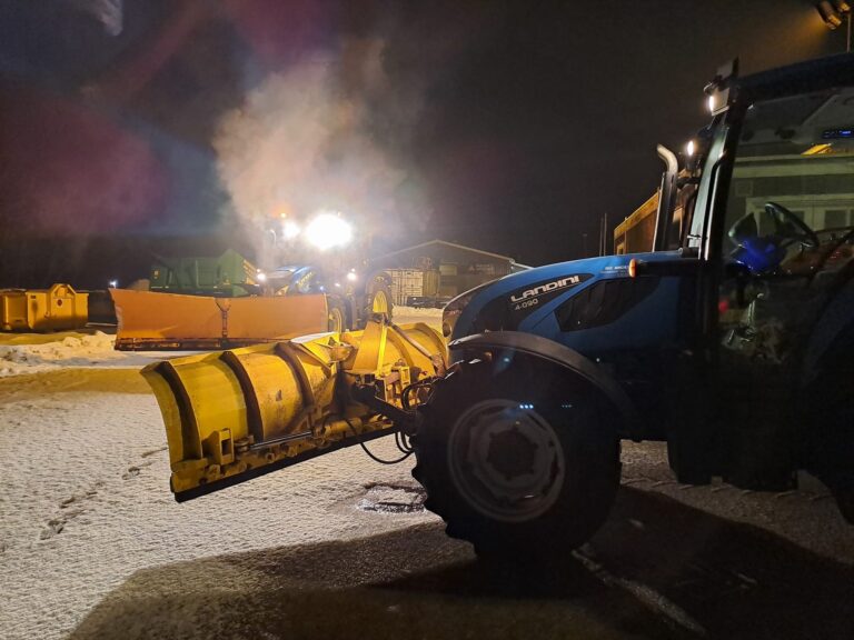 Traktor rydder sne om natten på parkeringsplads