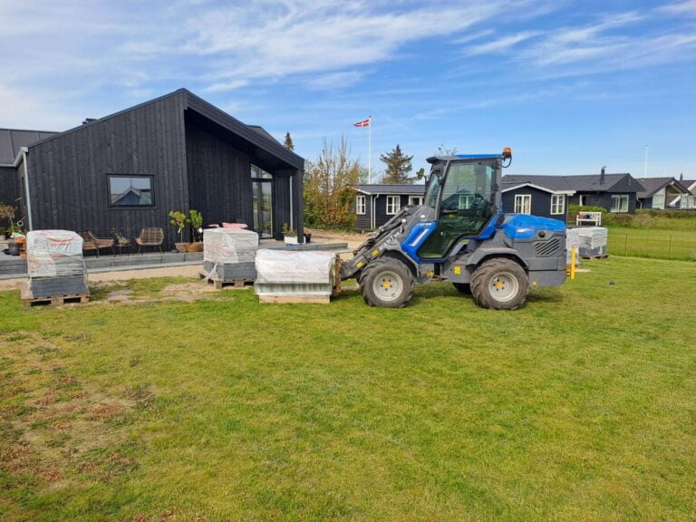 Minilæsser arbejder foran moderne sort hus