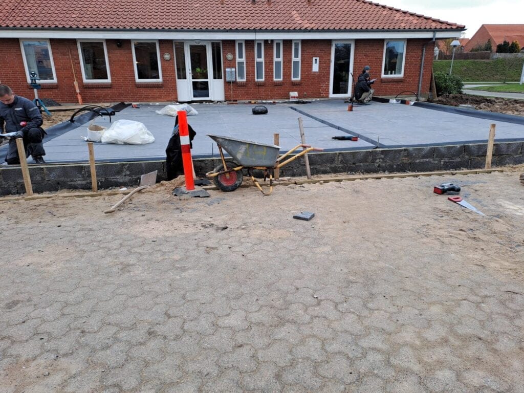 Håndværkere arbejder på ny bygningsterrasse foran hus