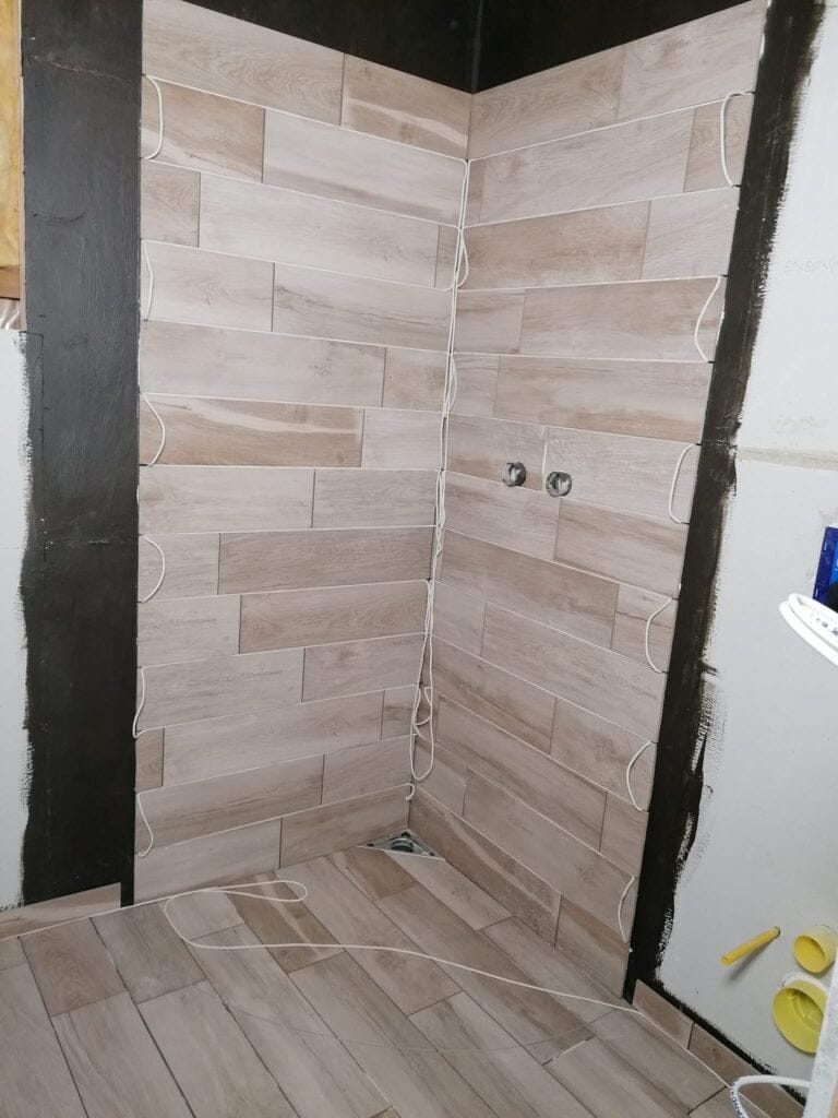 Hjørne af badeværelse med trælook fliser under installation