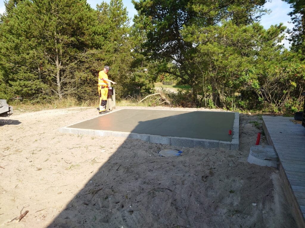 Arbejdemand glatter nyudstøbt betonplade i haveområde