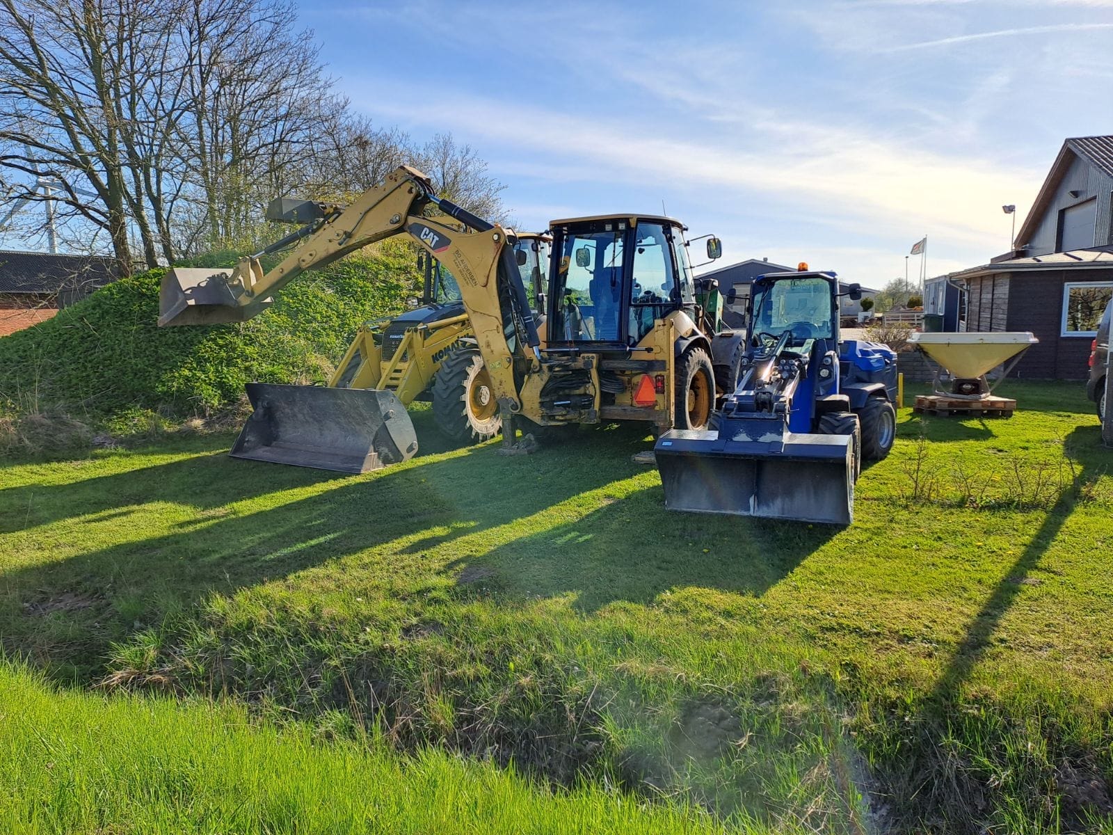 Gravemaskiner og traktor parkeret på grønt område