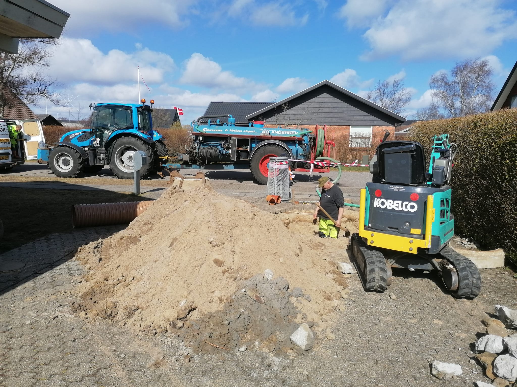 Arbejder graver med minigraver og traktor på byggeplads
