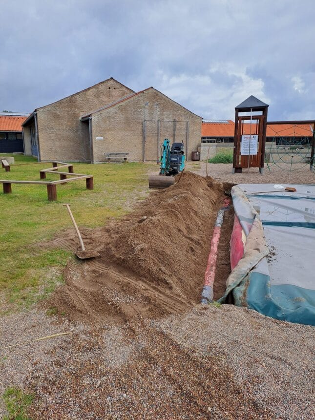 Gravemaskine arbejder ved legeplads og sandbunke