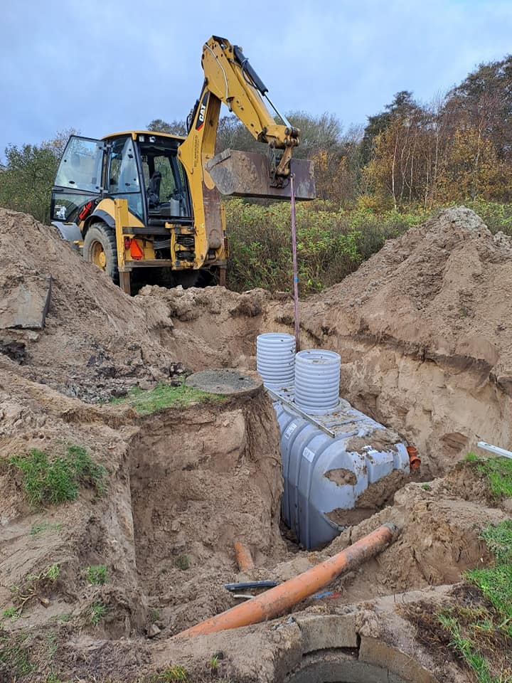Gravemaskine installerer septiktank i byggeudgravning